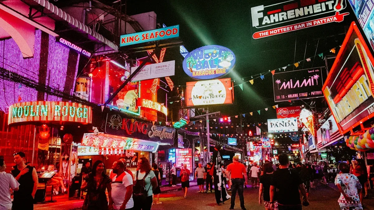 Pattaya Walking Street at night with vibrant neon signs from bars and restaurants, crowded pedestrian street full of tourists